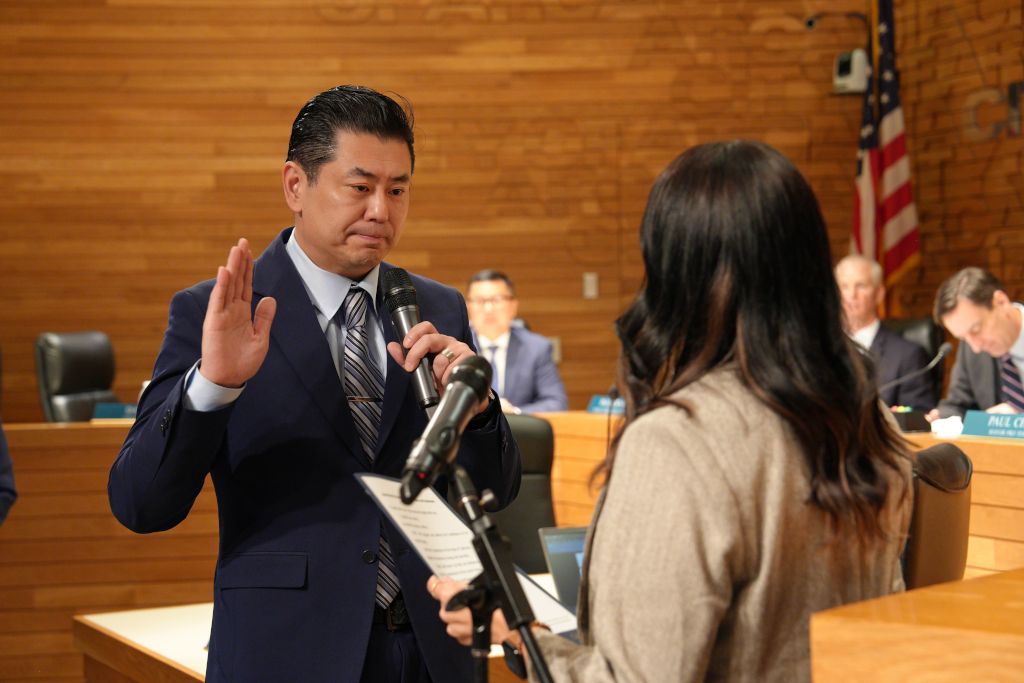 Paul Cheng Mayor Swearing In holding his hand as he takes the oath of office.